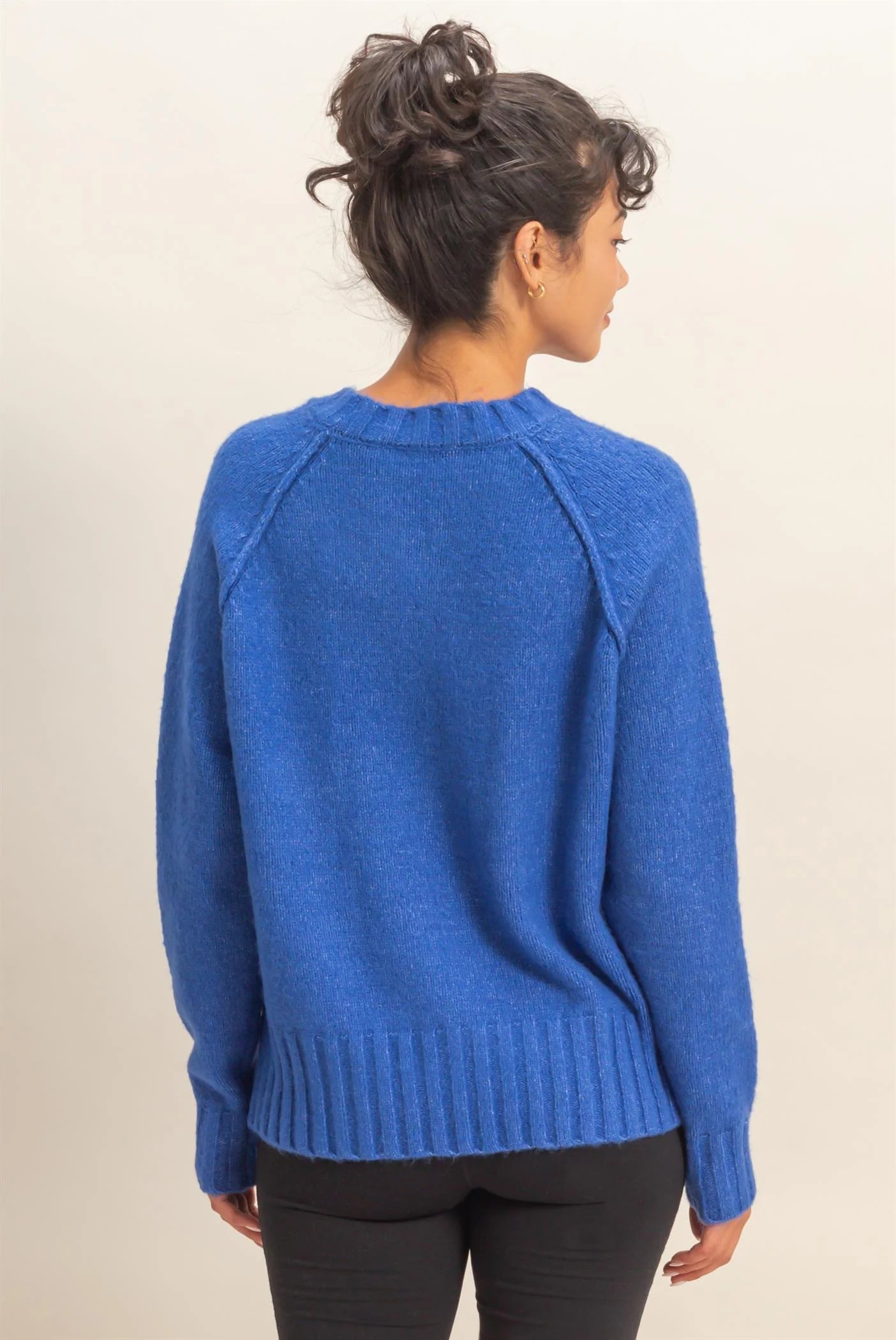 Person wearing a blue sweater from behind on a plain background
