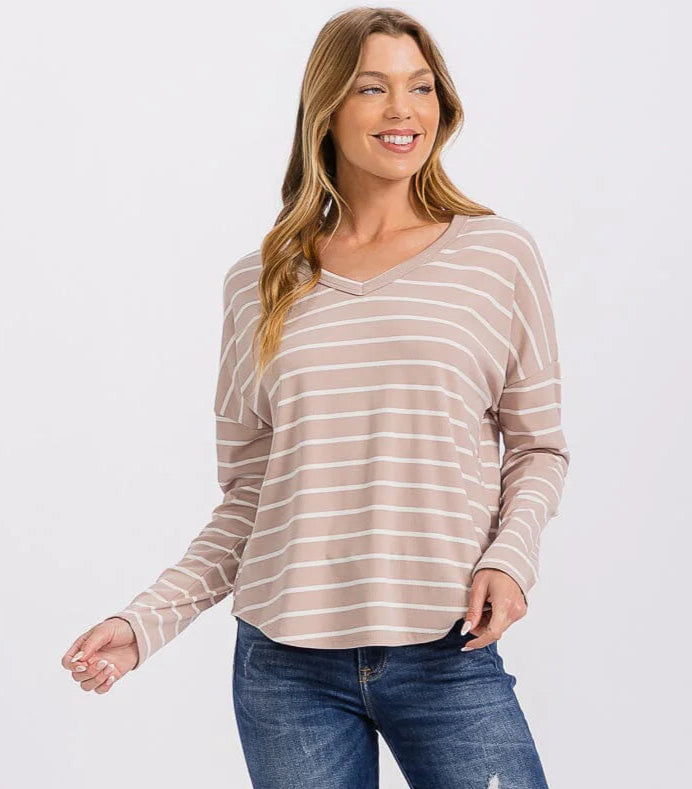 Woman wearing a striped long-sleeve top and blue jeans on a white background