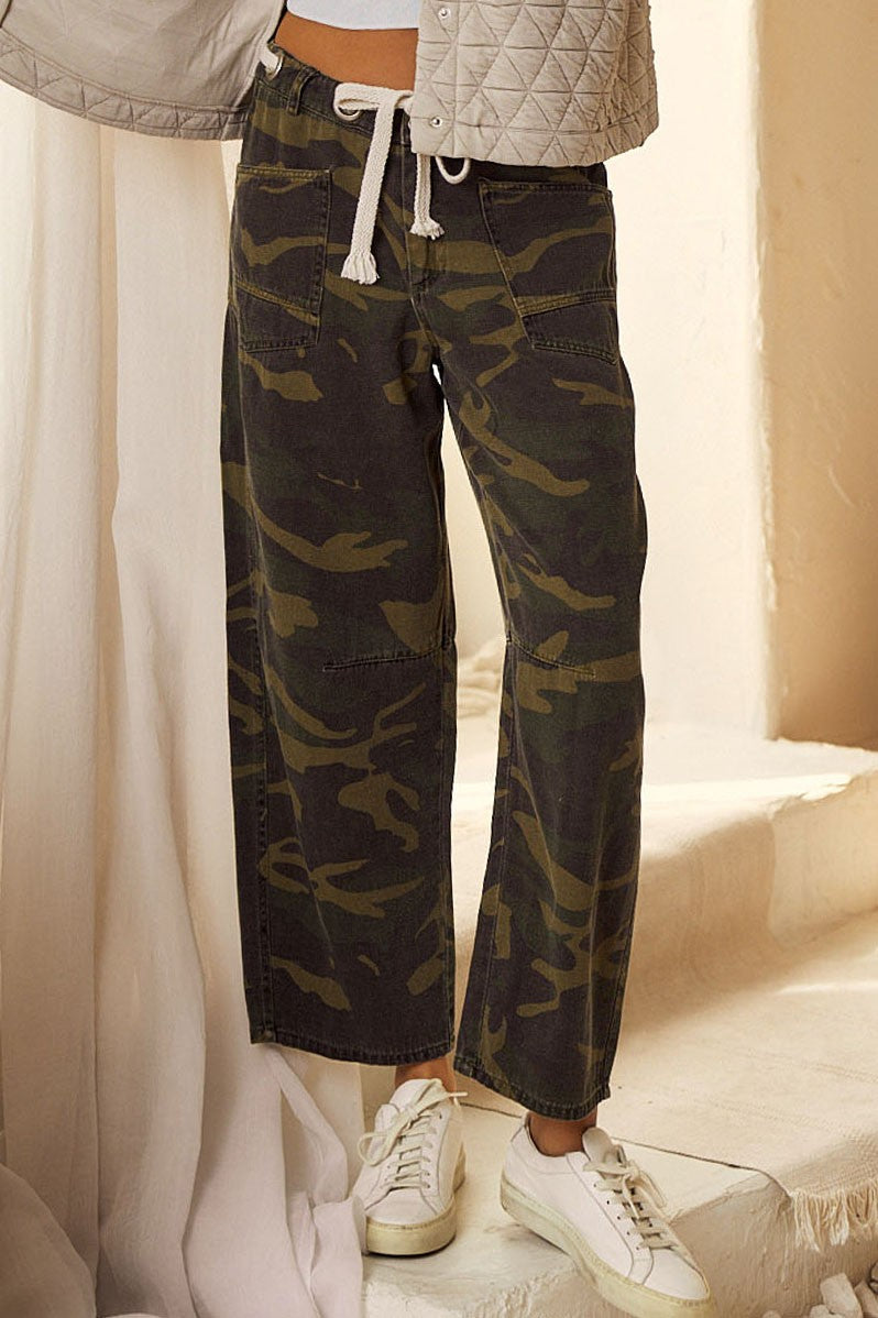 Person wearing camouflage pants with a neutral background