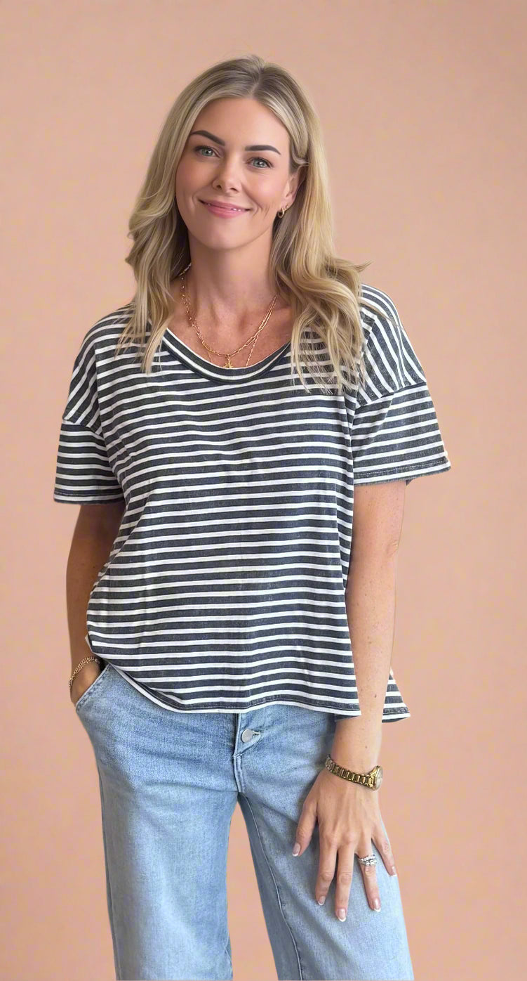 Woman wearing a striped shirt and jeans against a beige background