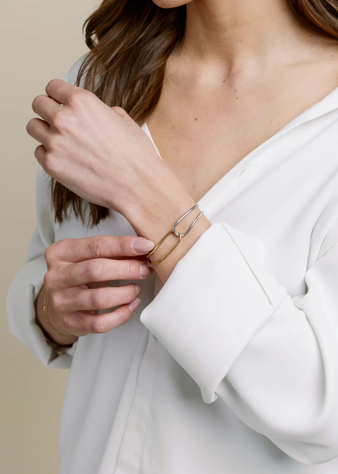 Person wearing a white top with a close-up of their wrist and hand, showing a mixed-metal bracelet from Vincent