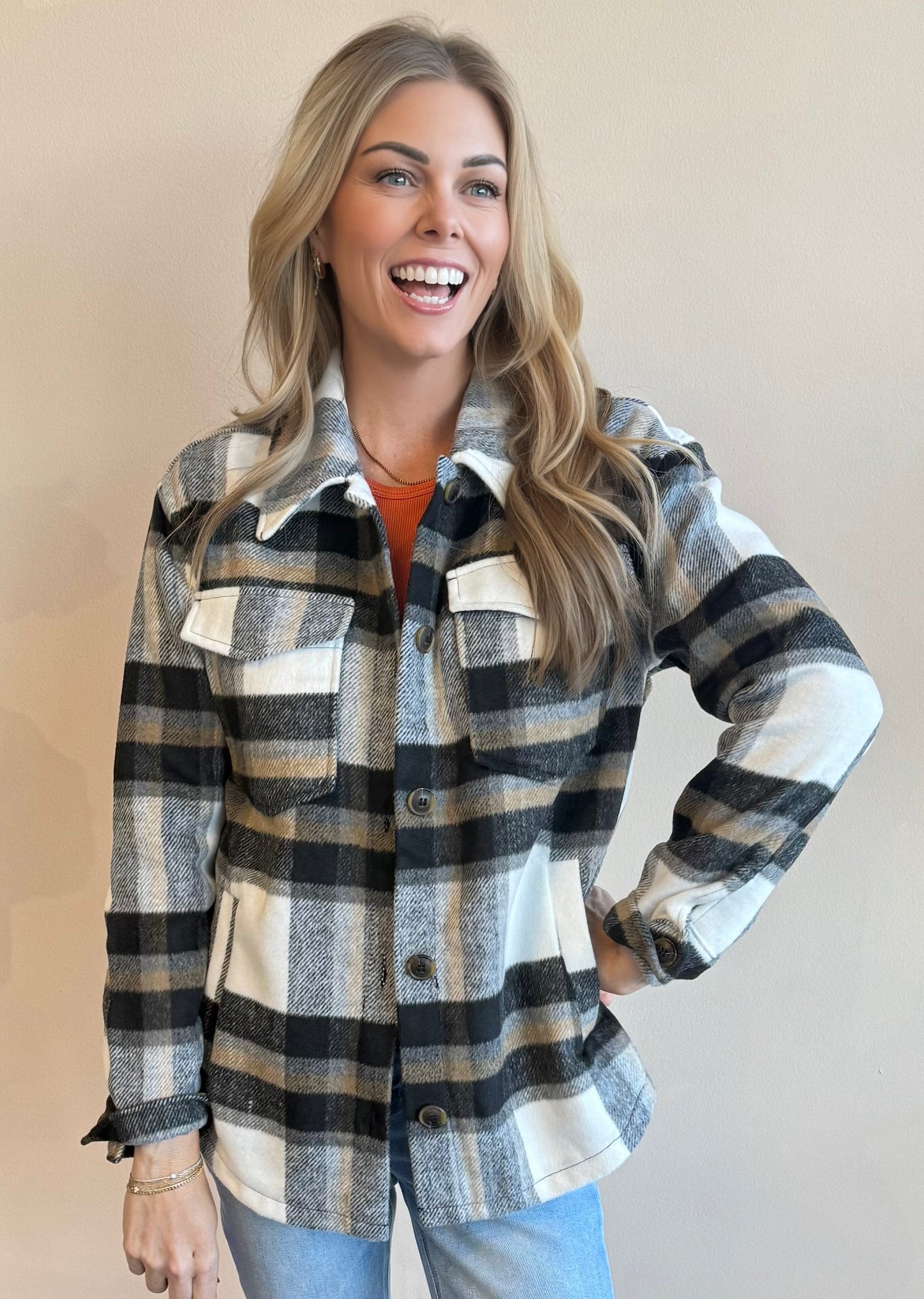 Woman wearing a black plaid shacket with a neutral background
