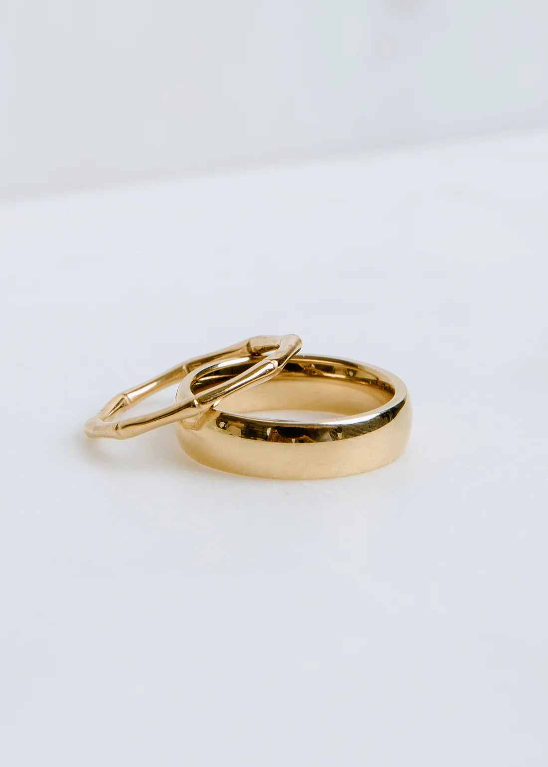 Two gold rings on a light gray background
