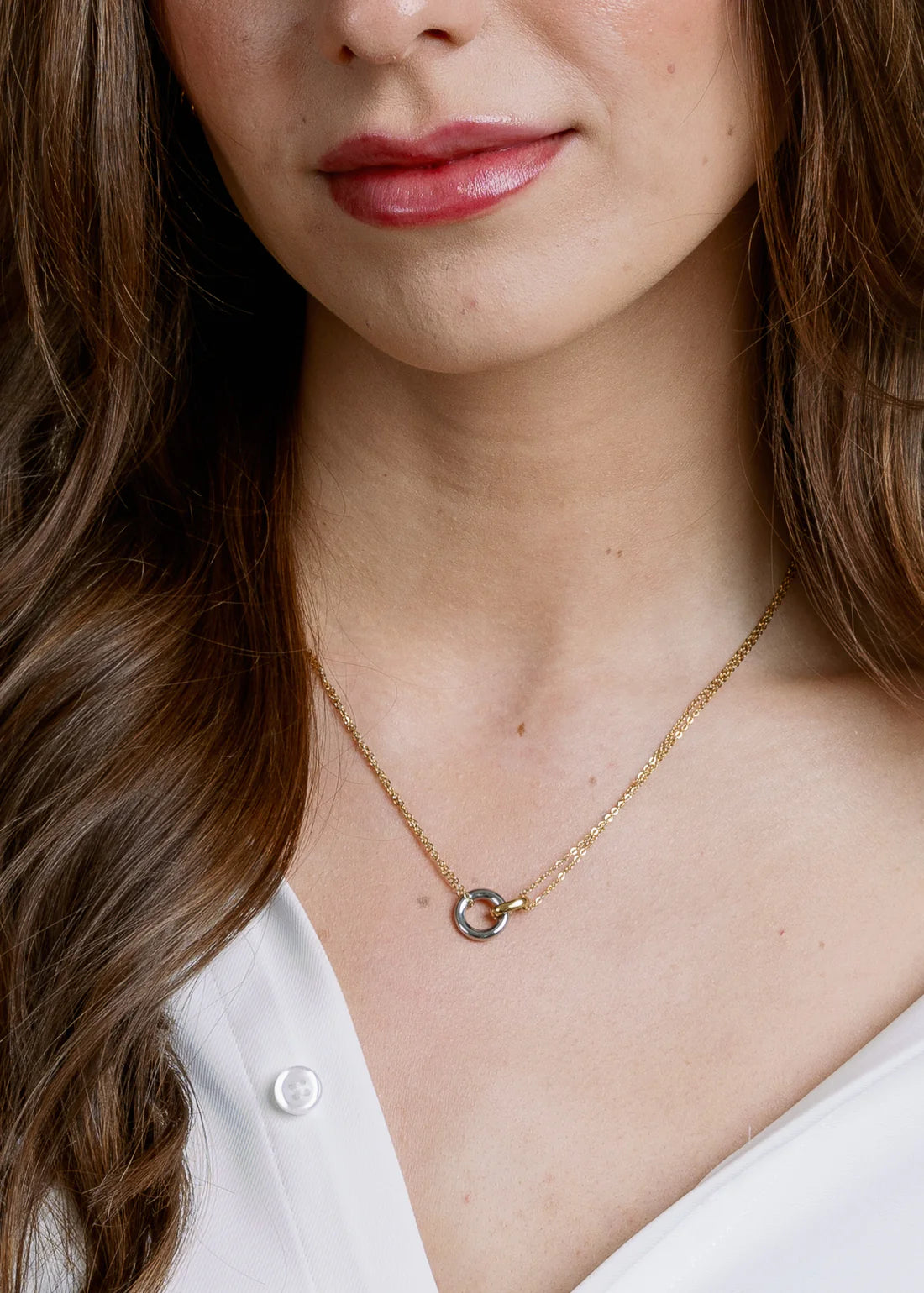 Close-up of a person wearing a mixed-metal necklace with hooked circles small pendant.