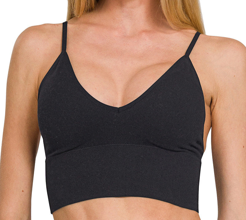 Woman wearing a black sports bra with text indicating removable pads on a white background