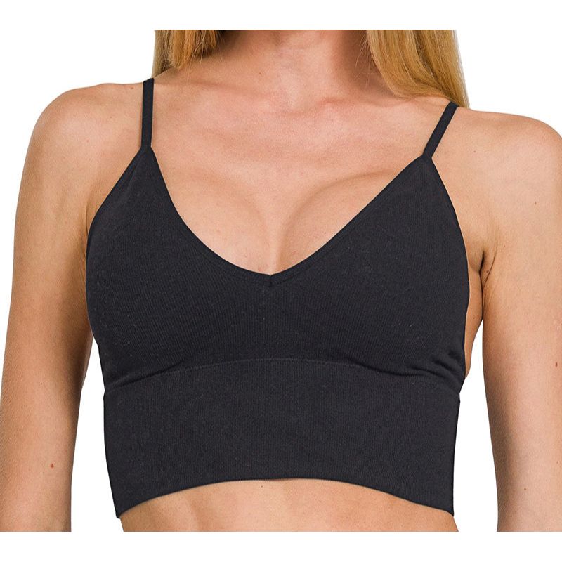 Woman wearing a black sports bra with text indicating removable pads on a white background