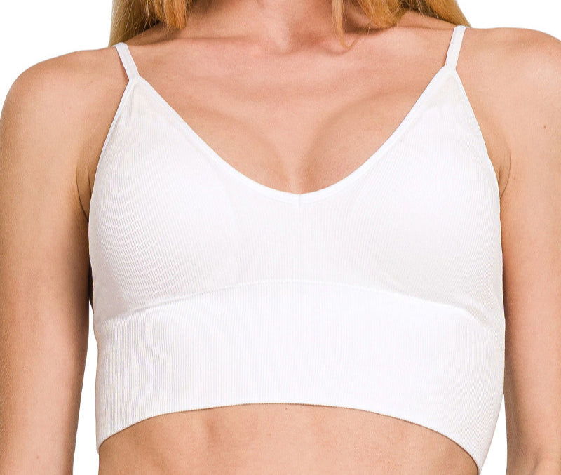 Woman wearing a white sports bra with text indicating removable bra pads.