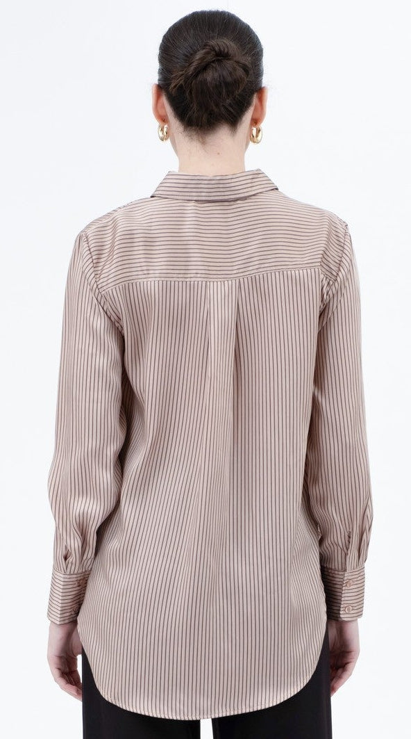 Person wearing a beige ribbed shirt and black pants on a white background