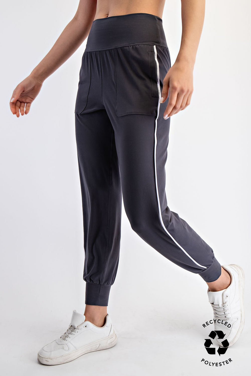 Person wearing dark gray Rae jogger pants with a white stripe on a white background