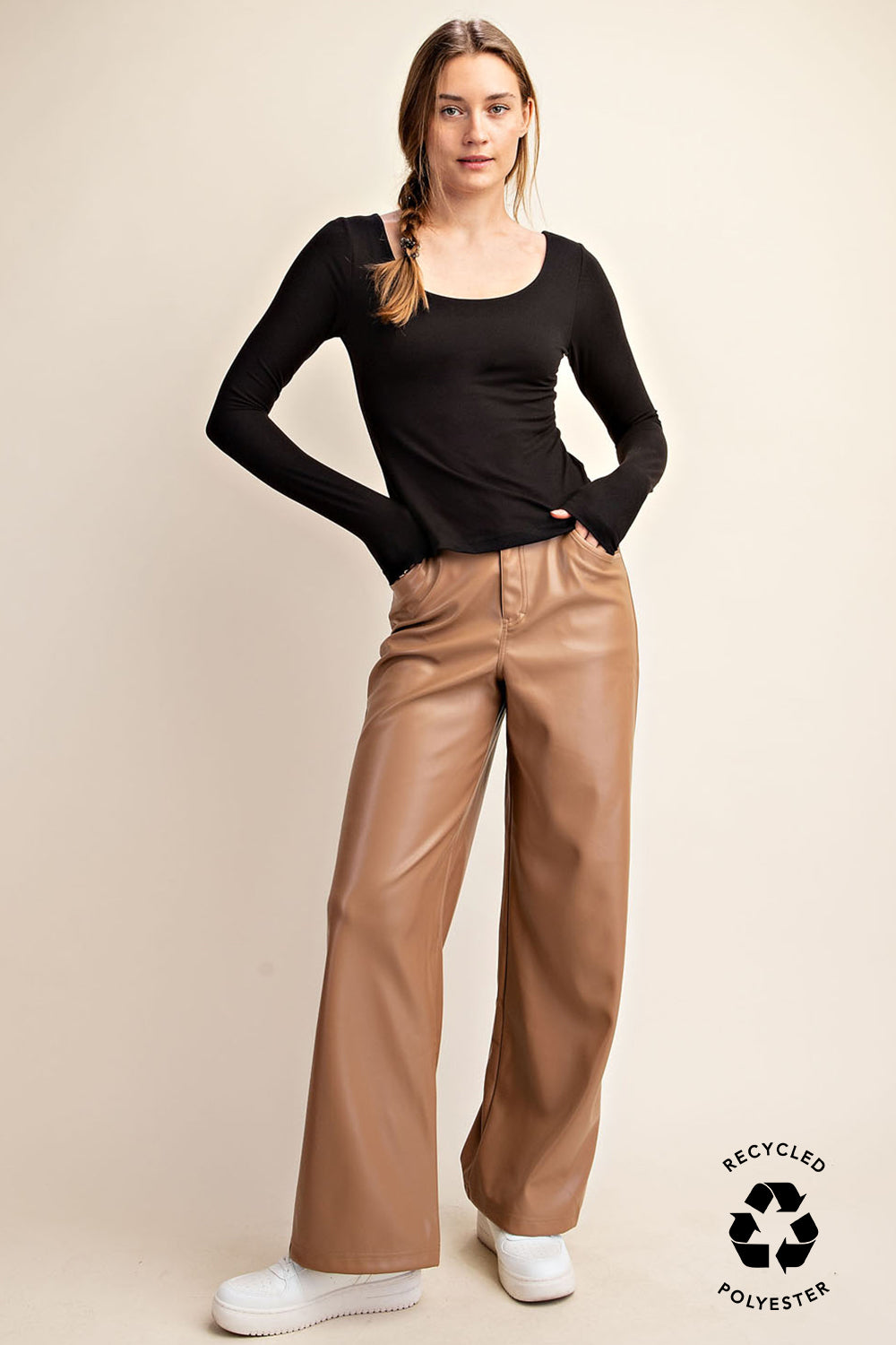 Woman wearing a rae butter soft black top and tan pants on a beige background with a recycled polyester label.