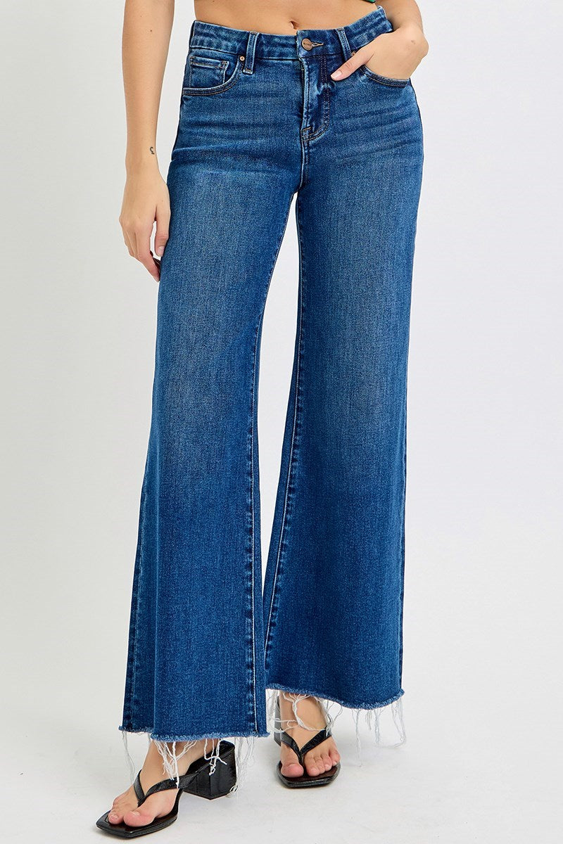 Risen Poppy Dark Blue jeans worn by a person on a white background wearing black sandals with a chunky heel
