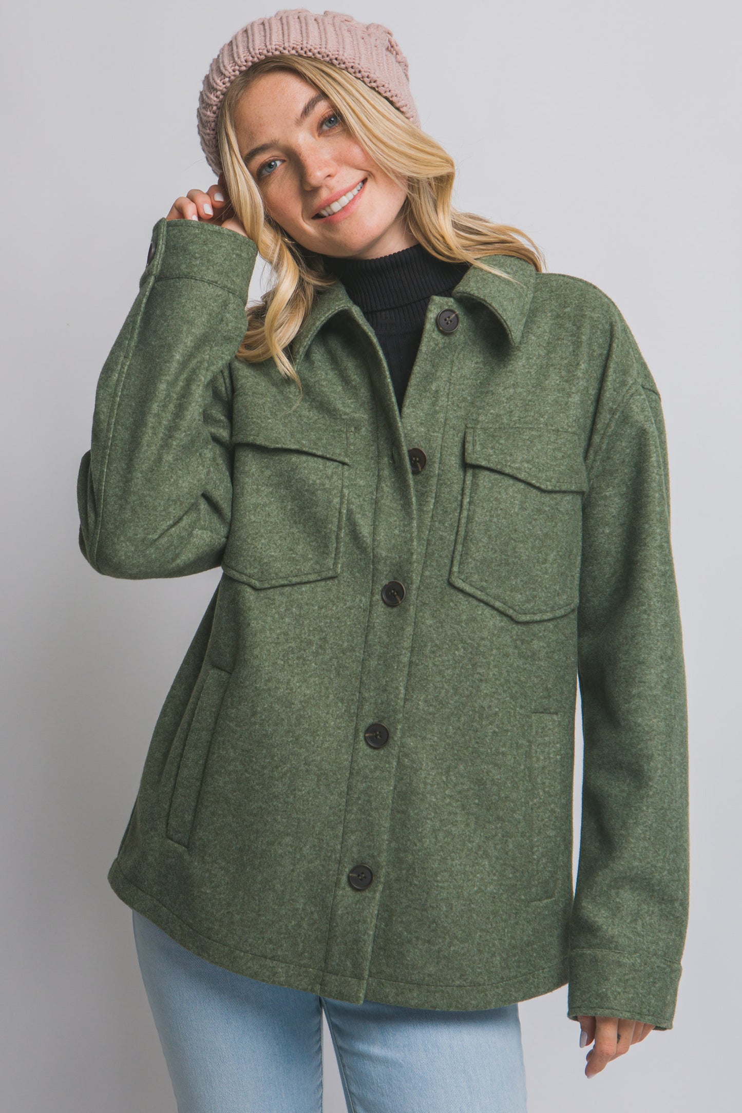 Woman wearing an olive green coat with a plain background