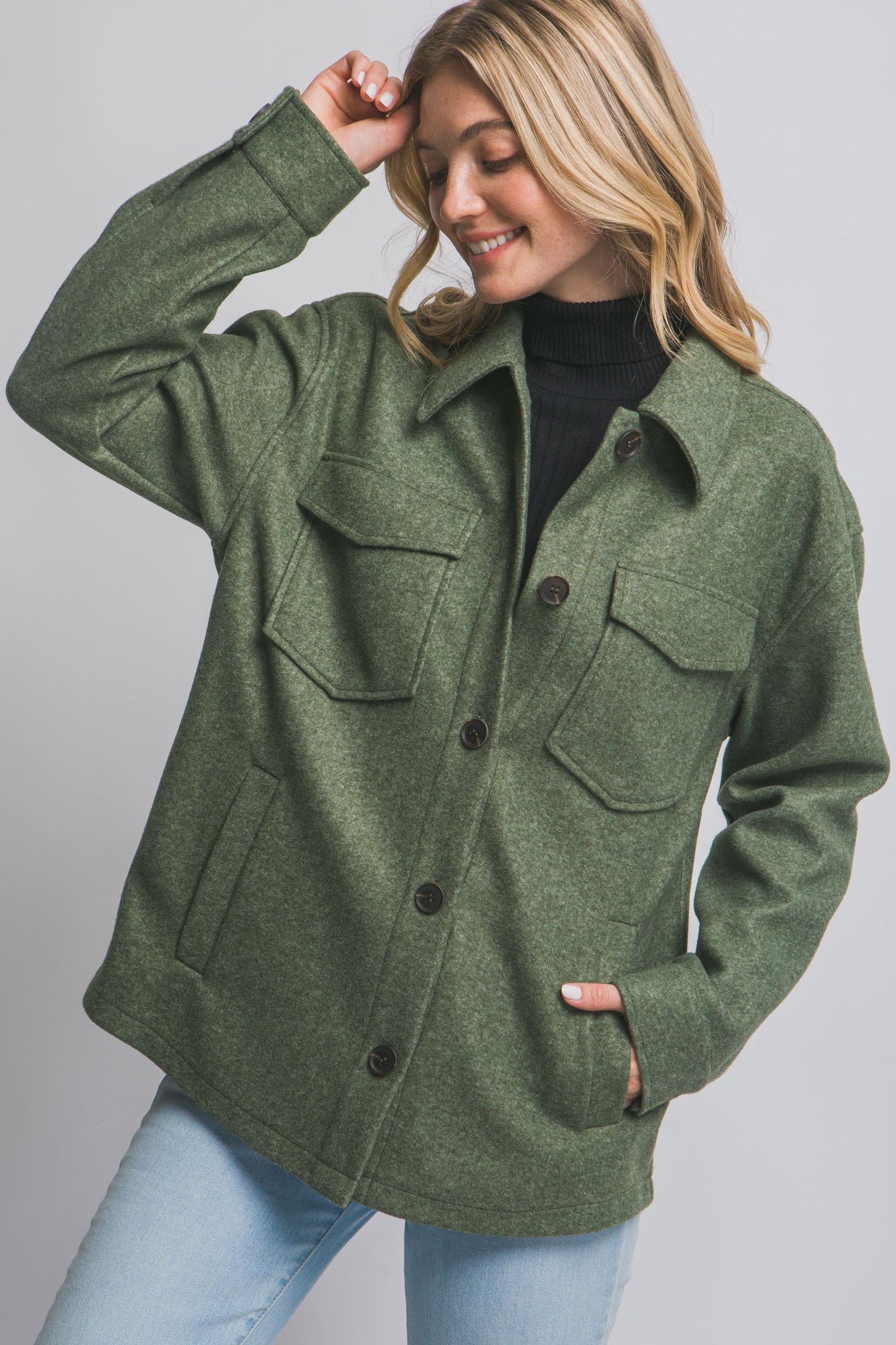 Woman wearing an olive green jacket with button details on a plain background
