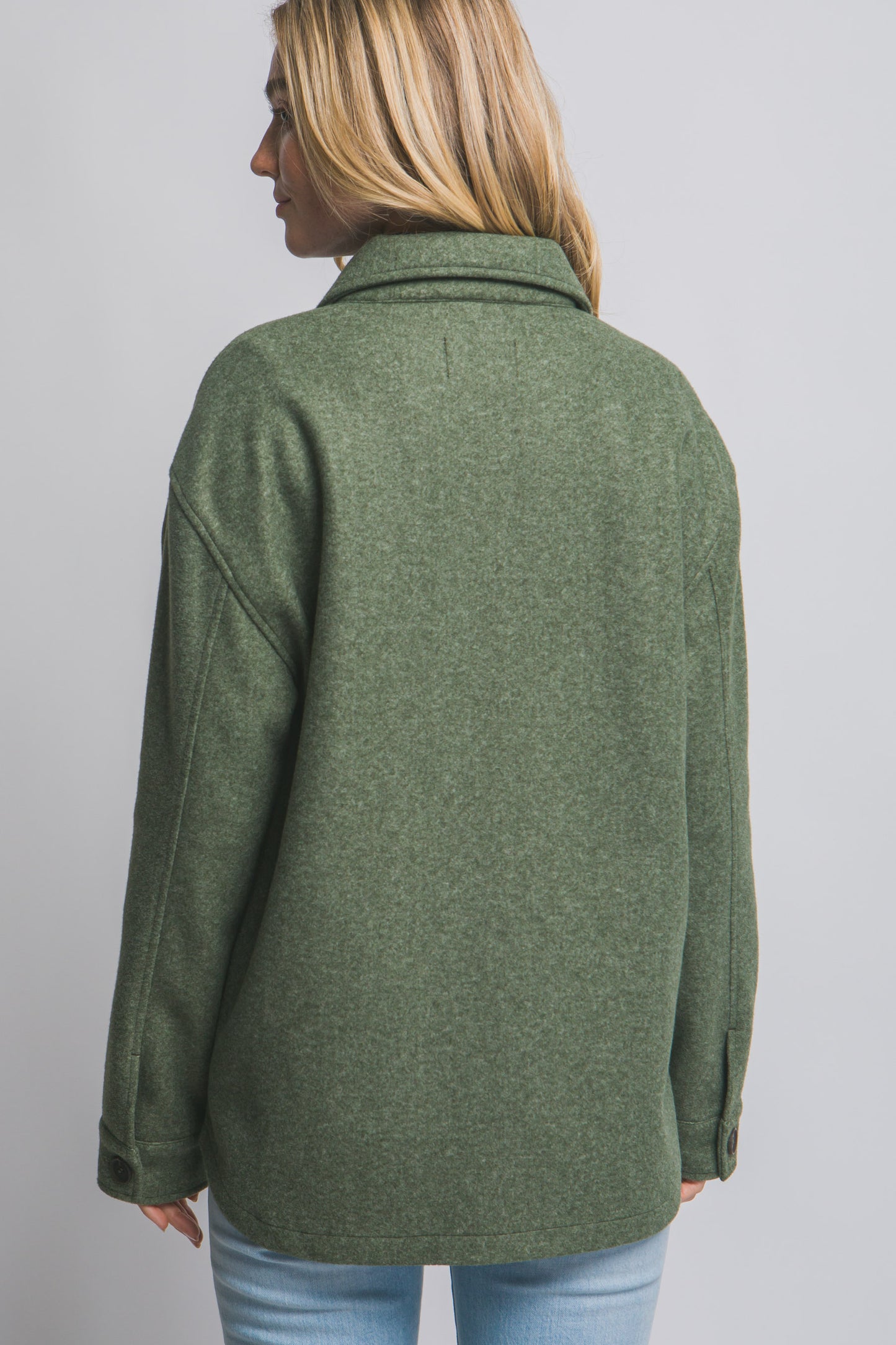 Person wearing an olive green jacket on a plain background
