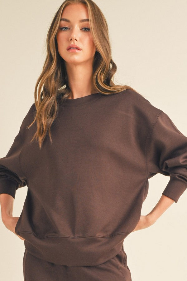 Woman wearing a brown sweatshirt against a plain background