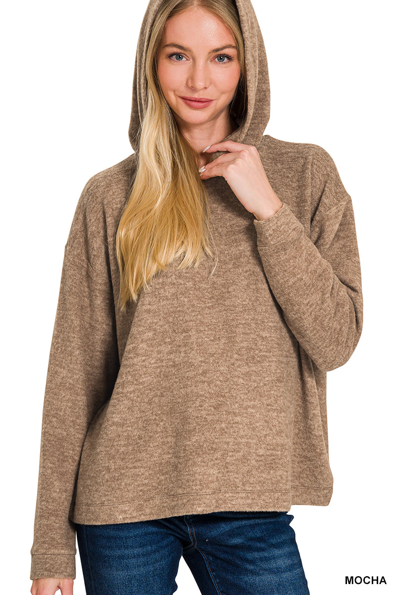 Woman wearing a mocha colored hoodie with a plain background