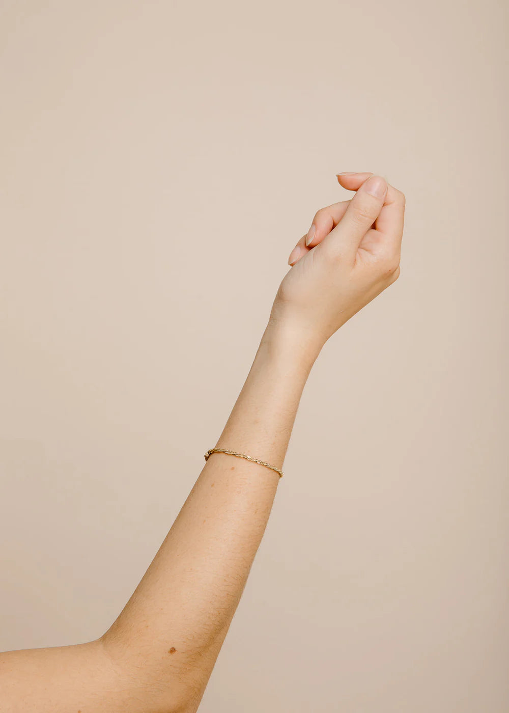 Hand and arm with a bracelet on a beige background
