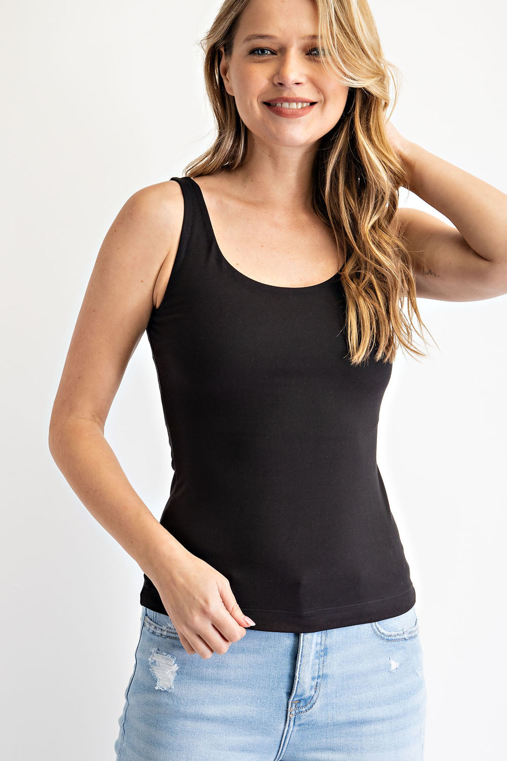 Woman wearing a black tank top and light blue jeans on a white background