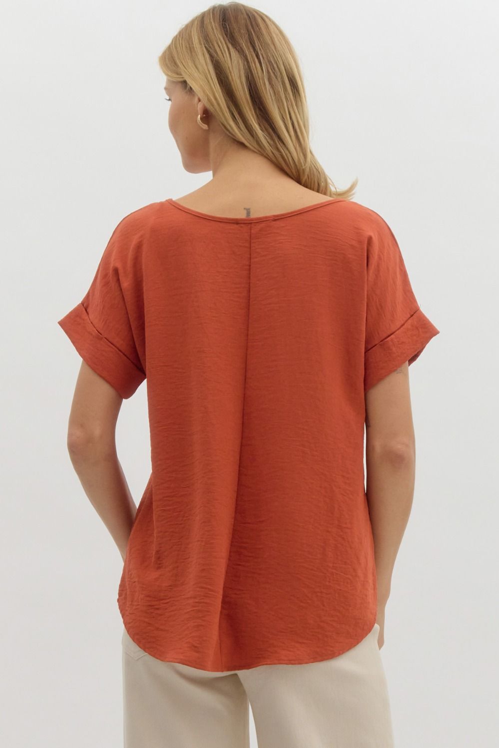Person wearing a rust-colored top on a white background