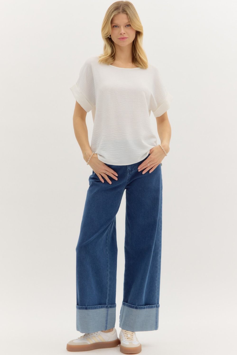 Woman wearing a white short-sleeve blouse and blue jeans on a white background