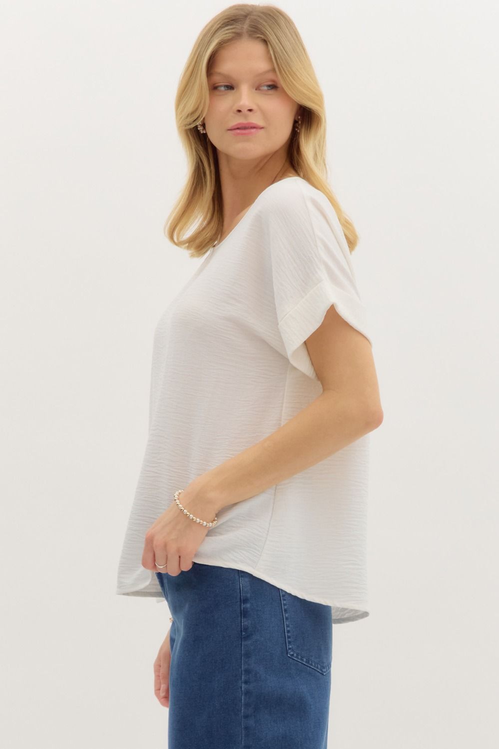 Woman wearing a white blouse and blue jeans on a plain background