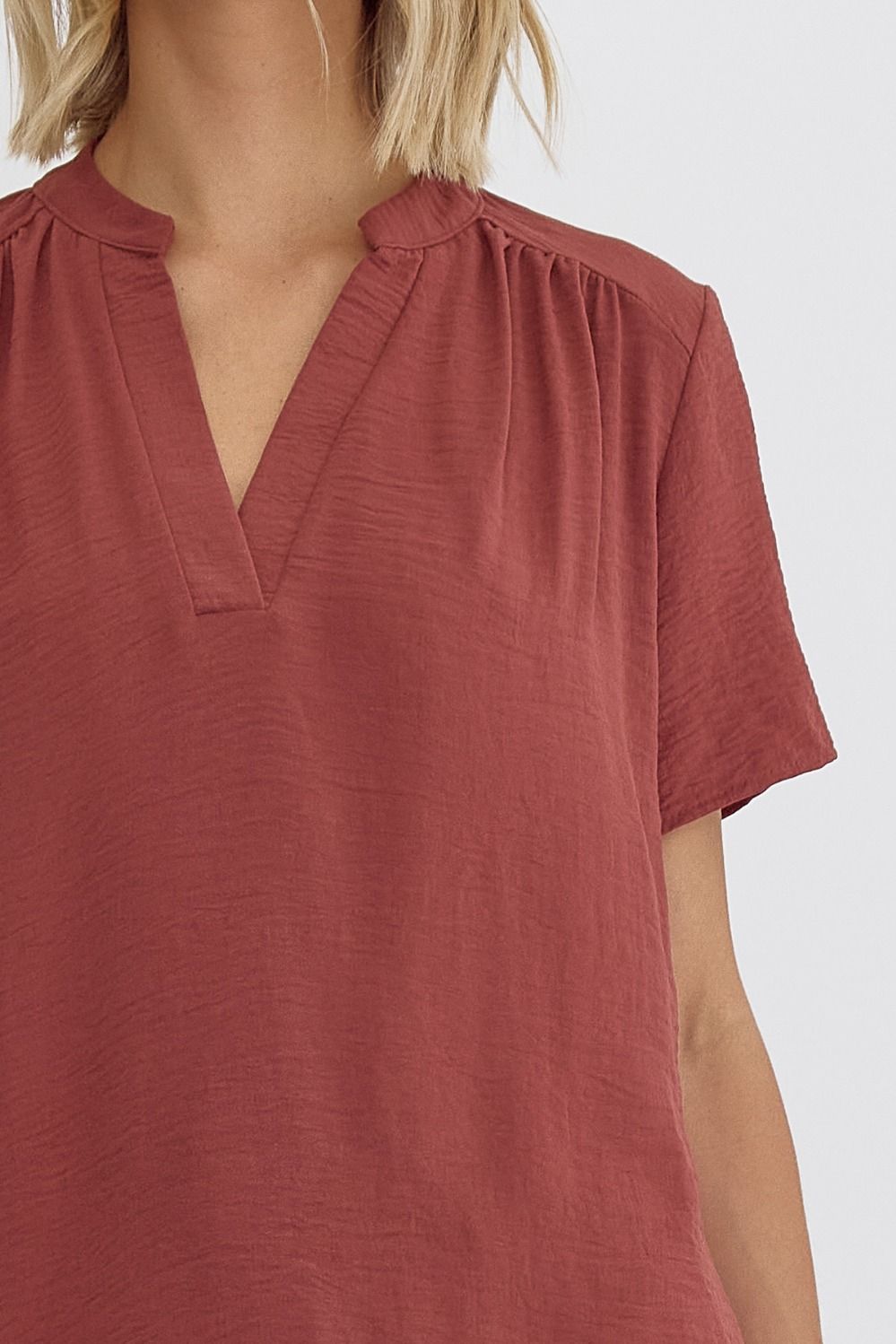 Reddish-brown top worn by a person on a white background