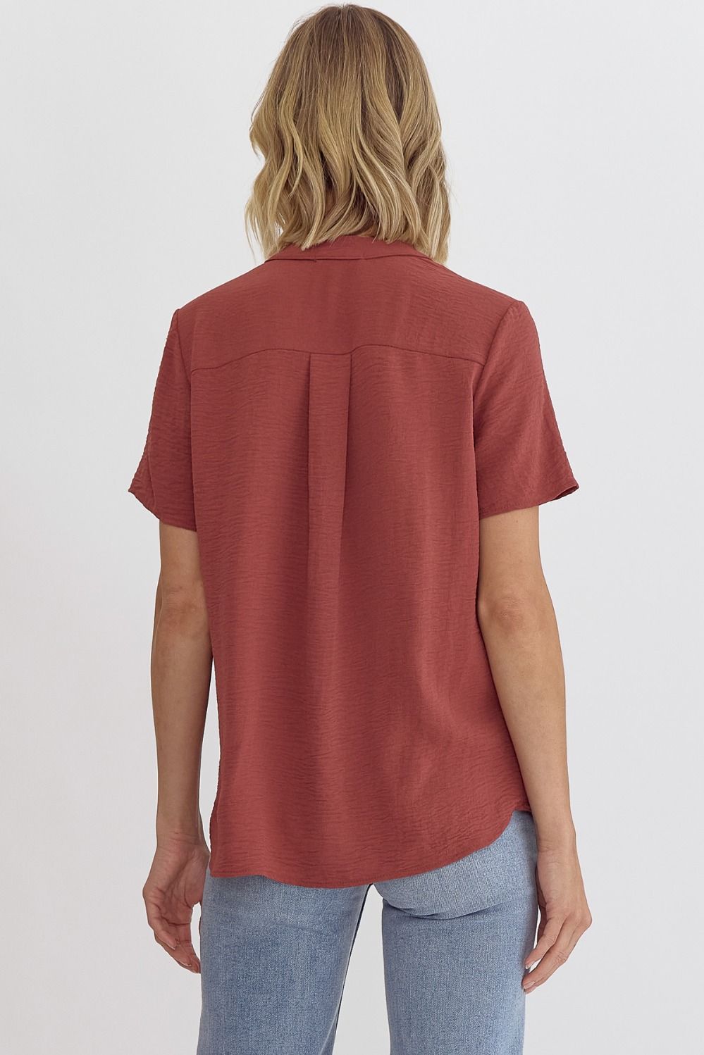 Person wearing a rust-colored short-sleeve shirt on a white background