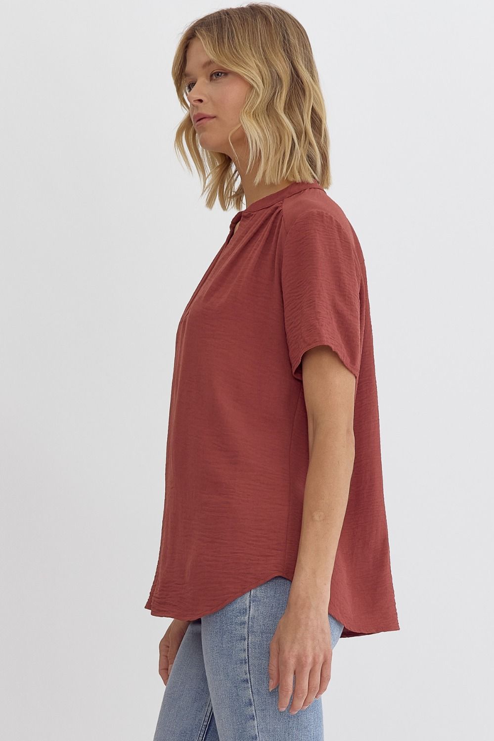 Woman wearing a rust-colored t-shirt and light blue jeans on a white background