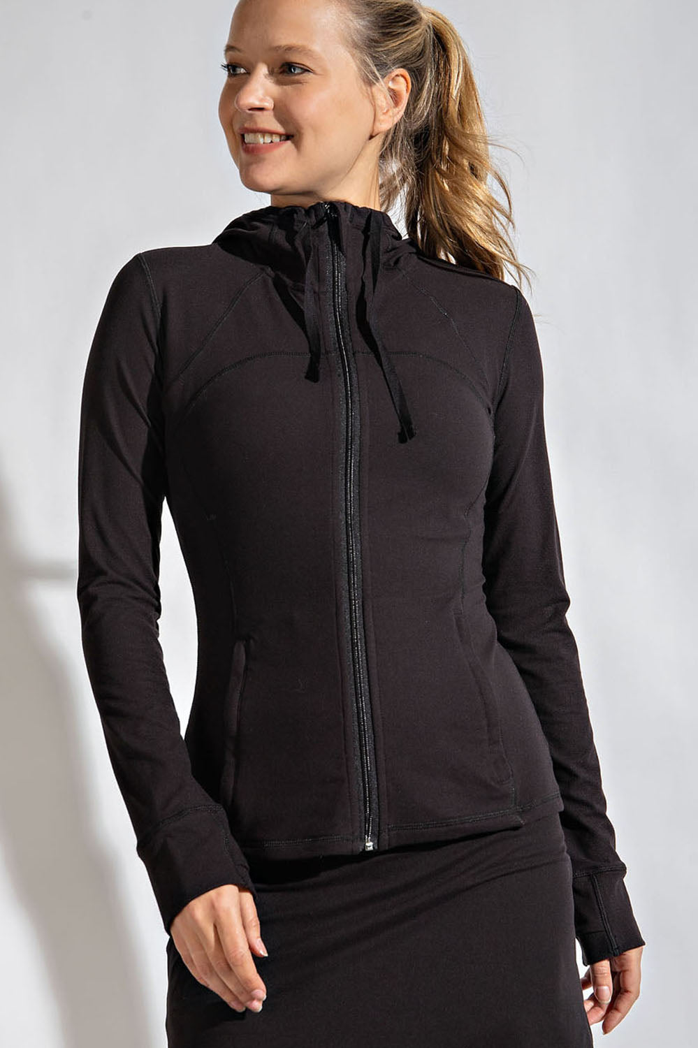 Woman wearing a black fitted jacket with a hoodie on a white background