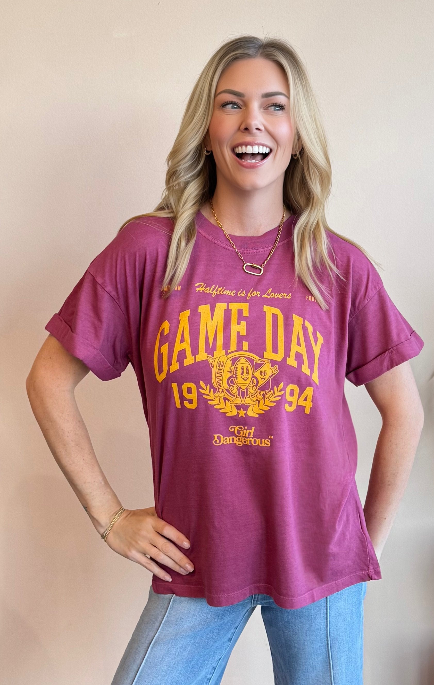 Woman wearing a maroon 'Game Day 1994' t-shirt with yellow text against a beige background