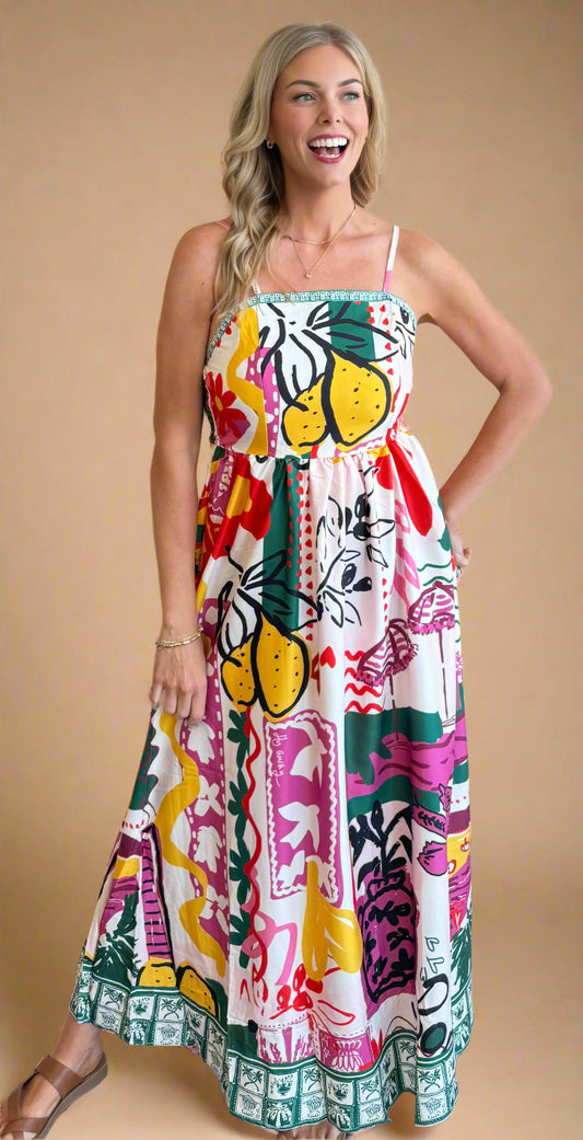 Woman wearing a colorful floral and fruit patterned dress against a beige wall.