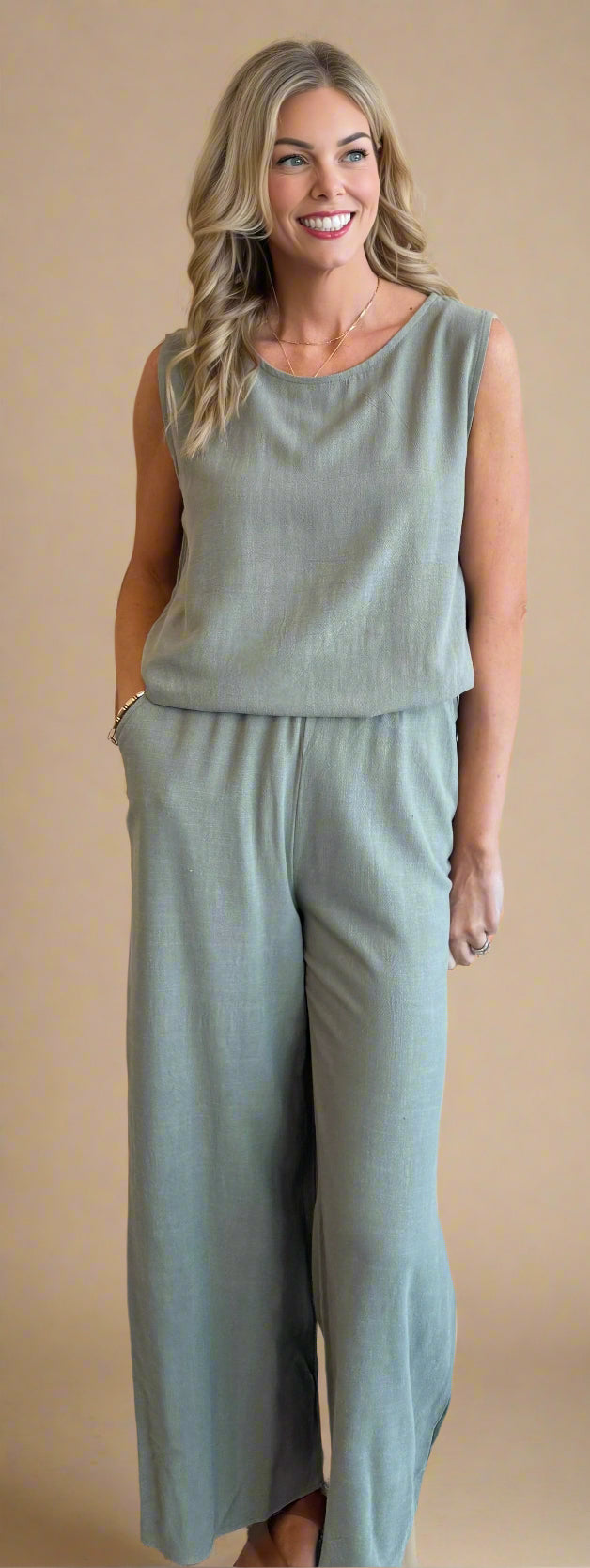 Woman wearing a green jumpsuit standing against a beige wall.
