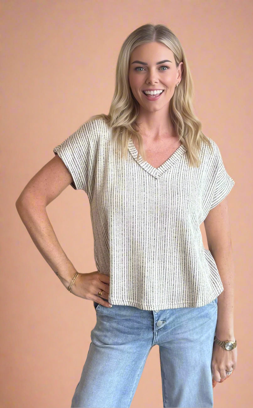 Woman wearing a striped shirt and jeans against a beige background