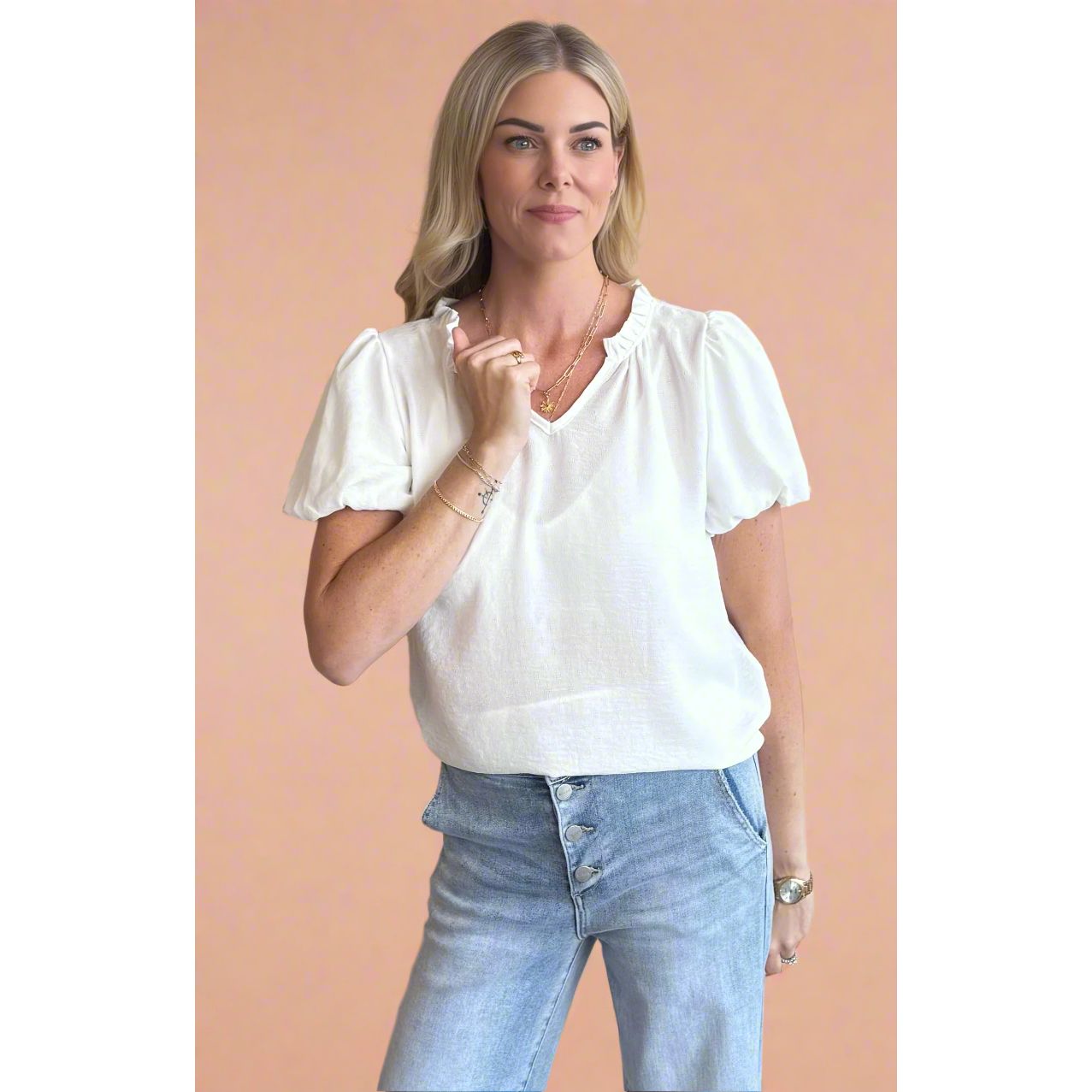 Woman wearing a white blouse and light blue jeans against a beige background