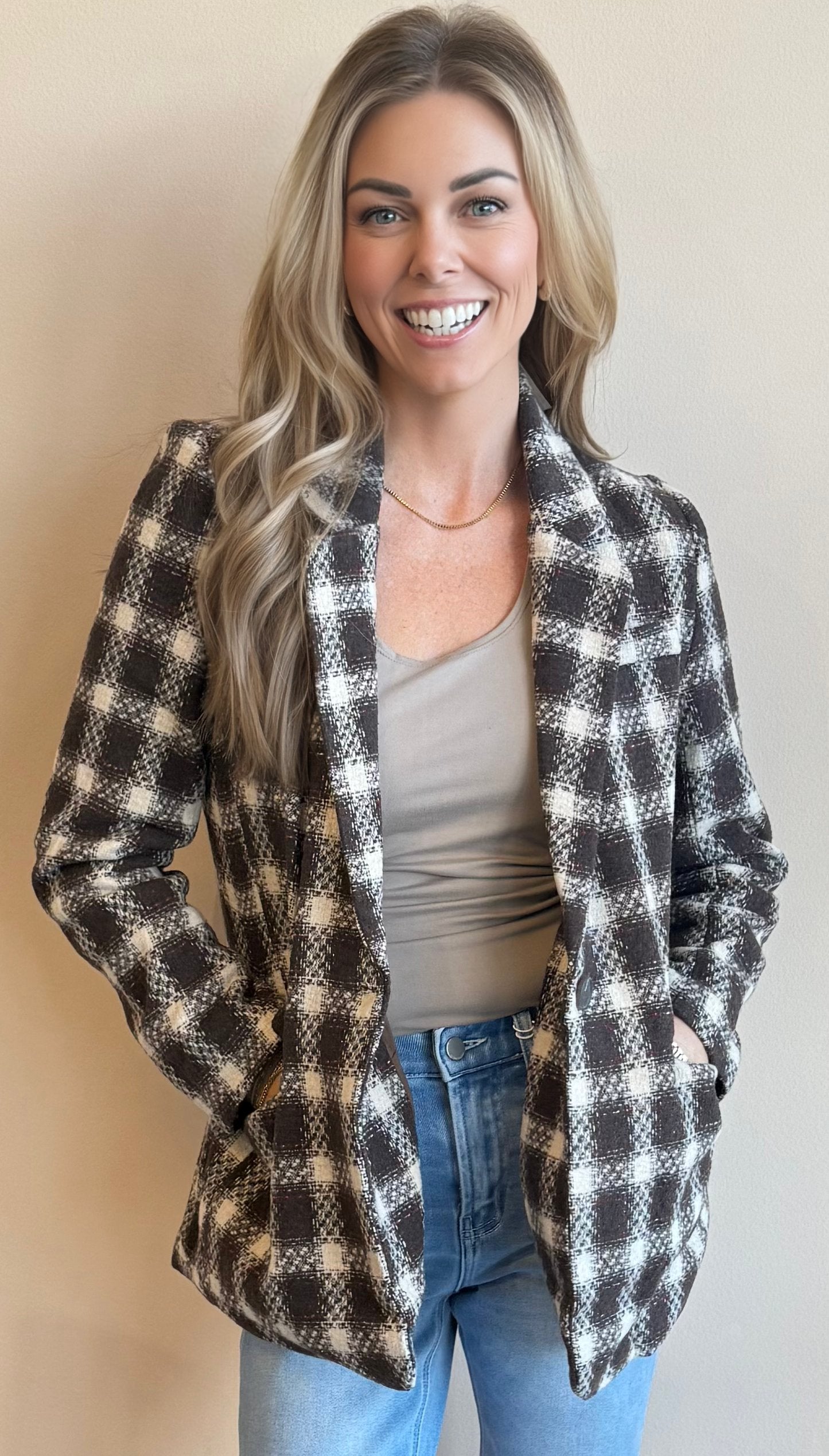 Woman wearing a chocolate brown checkered blazer against a plain background 