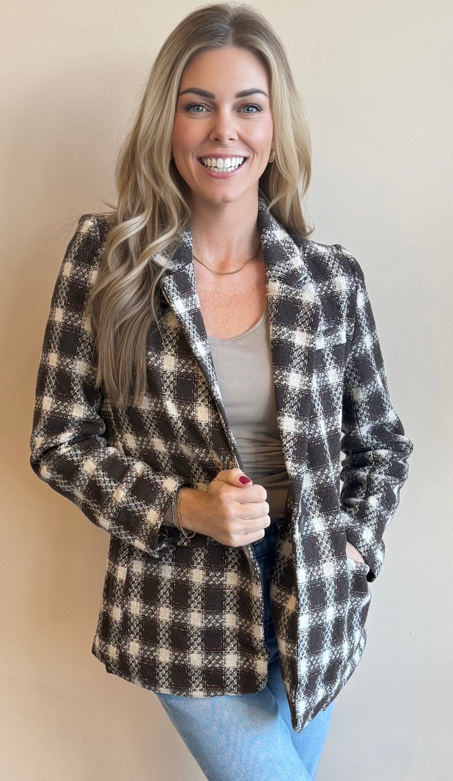 Woman wearing a chocolate brown checkered blazer against a plain background