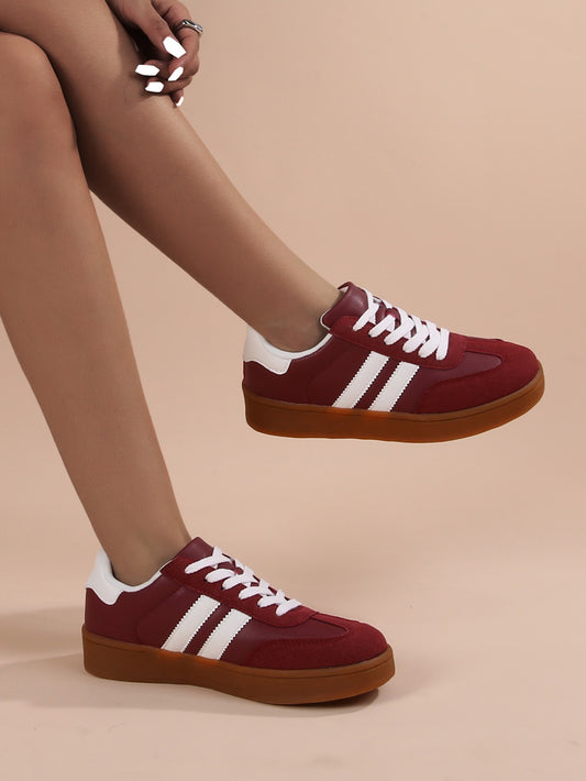 Red sneakers with white stripes worn by a person on a beige background