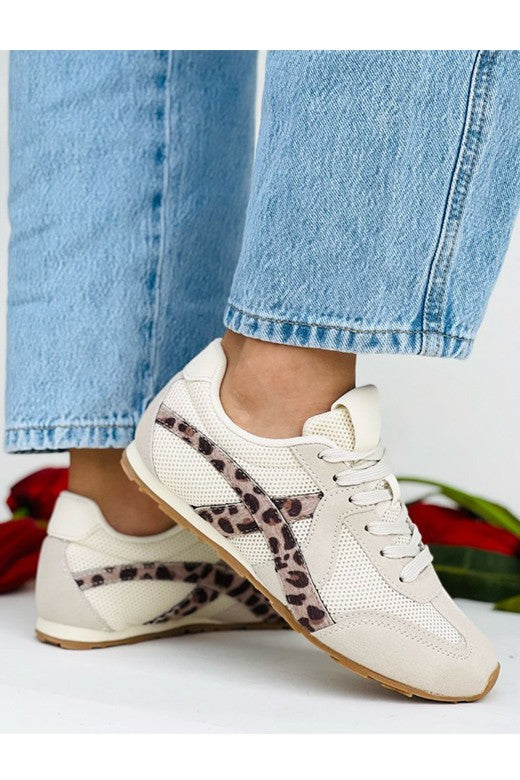 White sneakers with leopard print accents worn with light blue jeans on a white background.