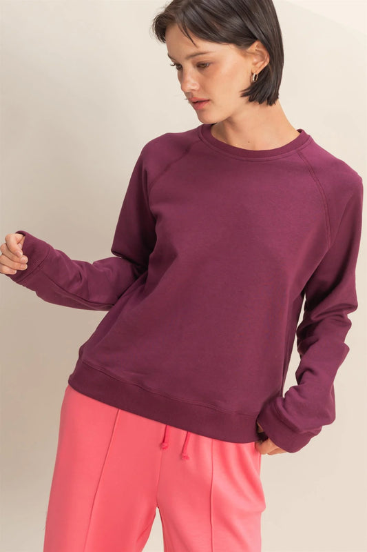 Person wearing a dark cherry sweatshirt and pink pants on a plain background
