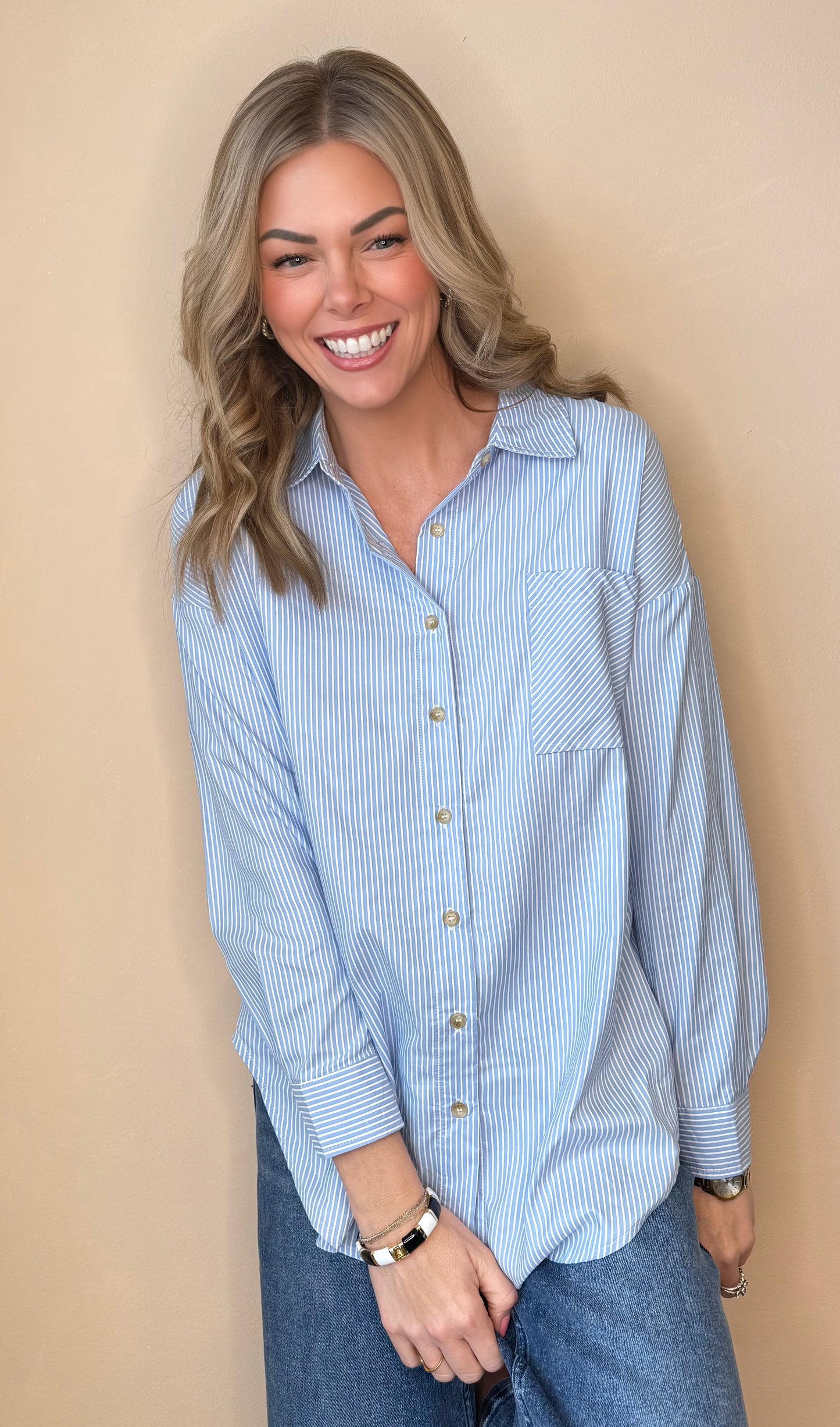 Woman wearing a light blue checkered shirt against a beige background