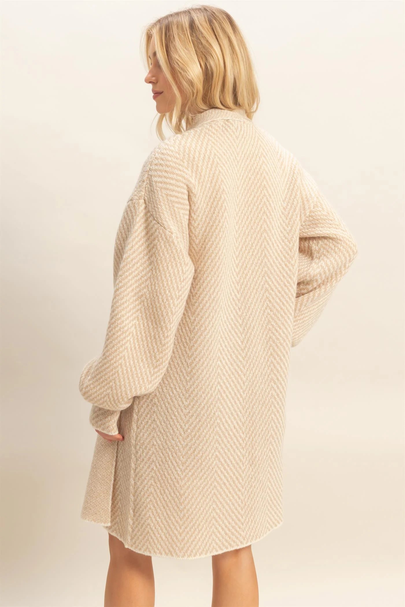 Woman wearing a beige knitted cardigan against a plain background