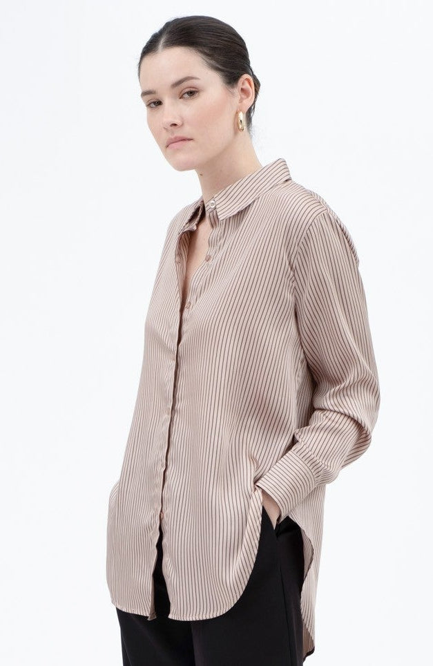 Woman wearing a beige shirt and black pants on a white background