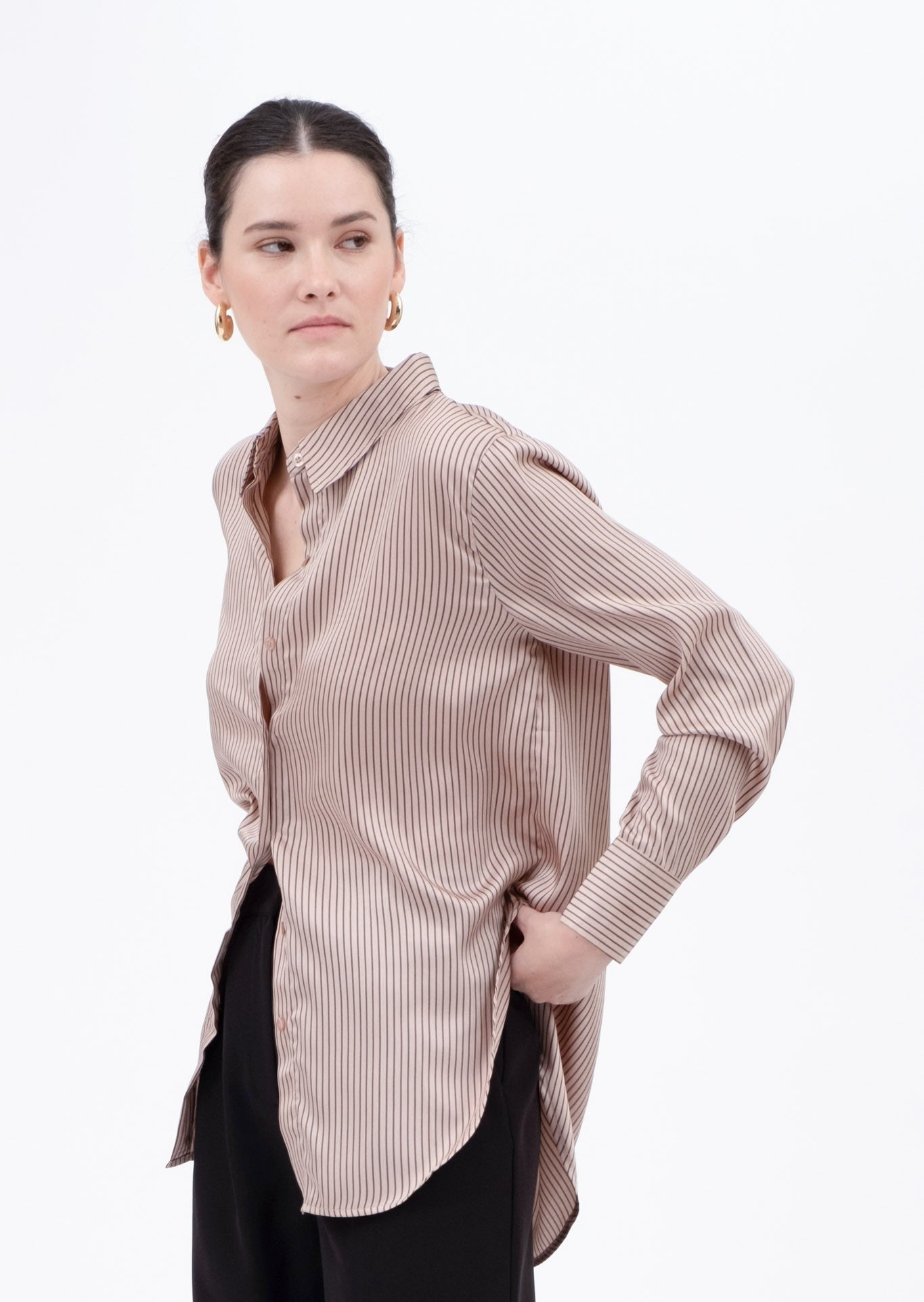 Woman wearing a light pink striped shirt with black pants on a white background