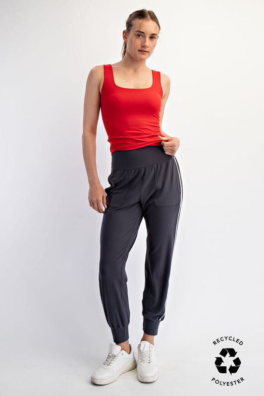Woman wearing a red tank top and gray jogger Rae pants on a white background with 'Recycled Polyester' label.