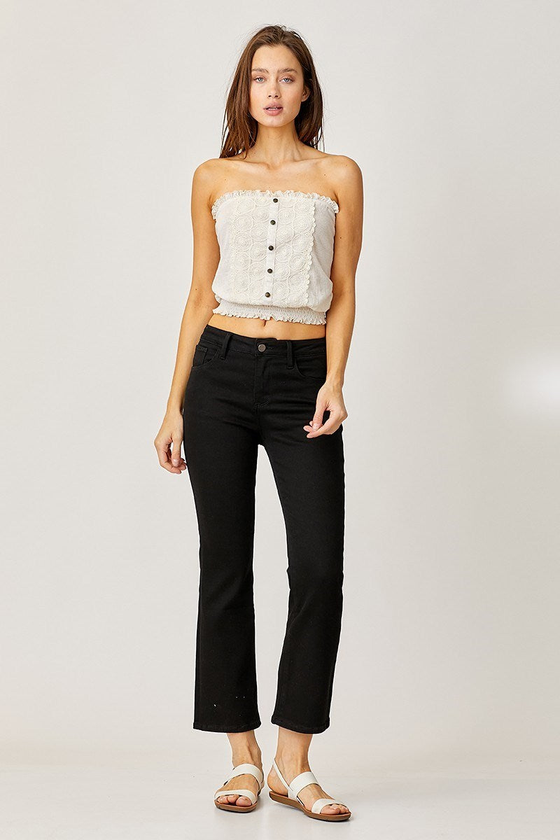 Woman wearing a white strapless top and Risen Jeans on a plain background