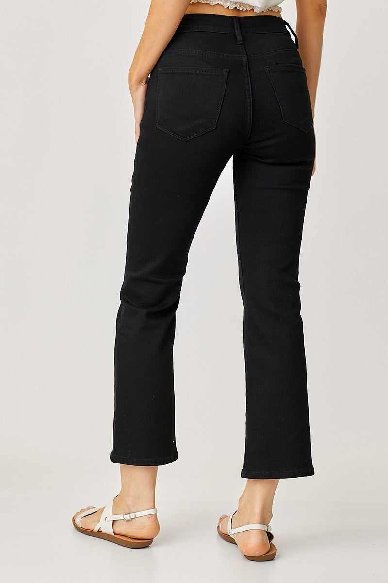 Black risen jeans worn by a person on a plain background