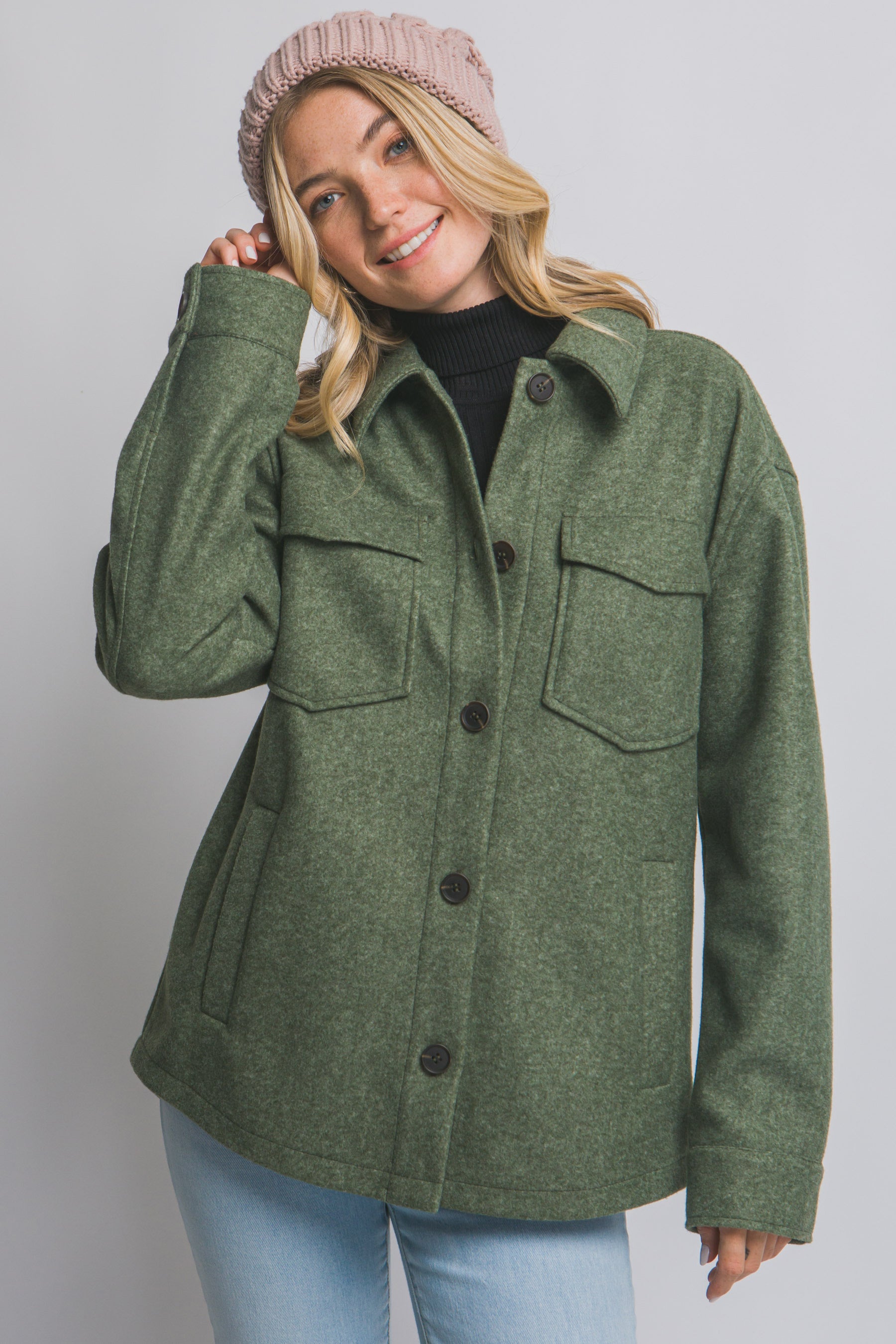 Woman wearing an olive green coat with a plain background