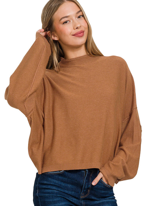Woman wearing a brown sweater and blue jeans on a white background