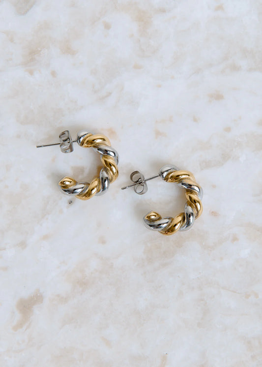 Pair of gold and silver hoop earrings on a marble surface