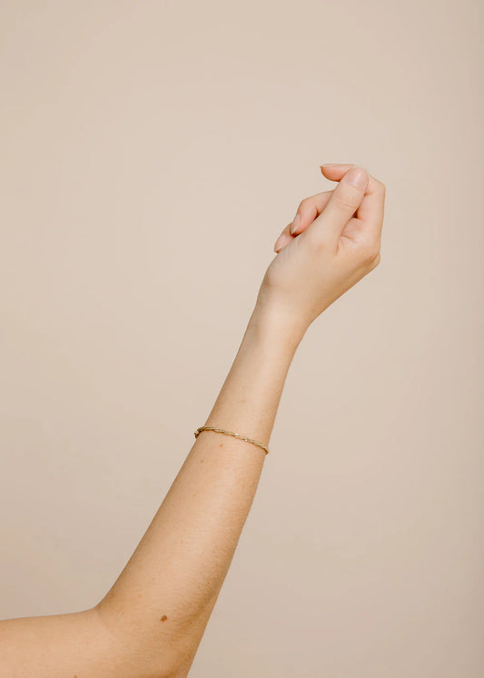 Hand and arm with a bracelet on a beige background